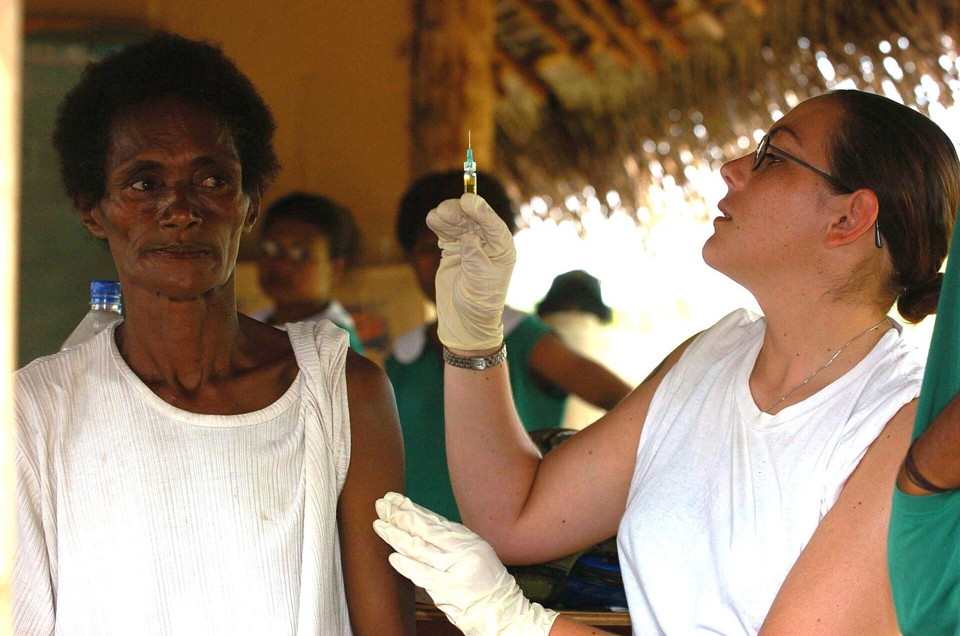 A U.S. Navy corpsman in gloves preparing a syringe of measles, mumps and rubella vaccine