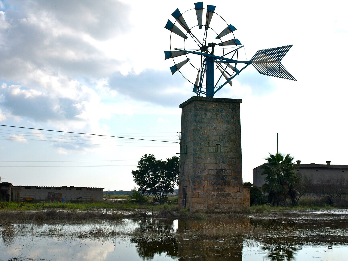 Floodwater covering a road and fields near an old windmill in Mallorca