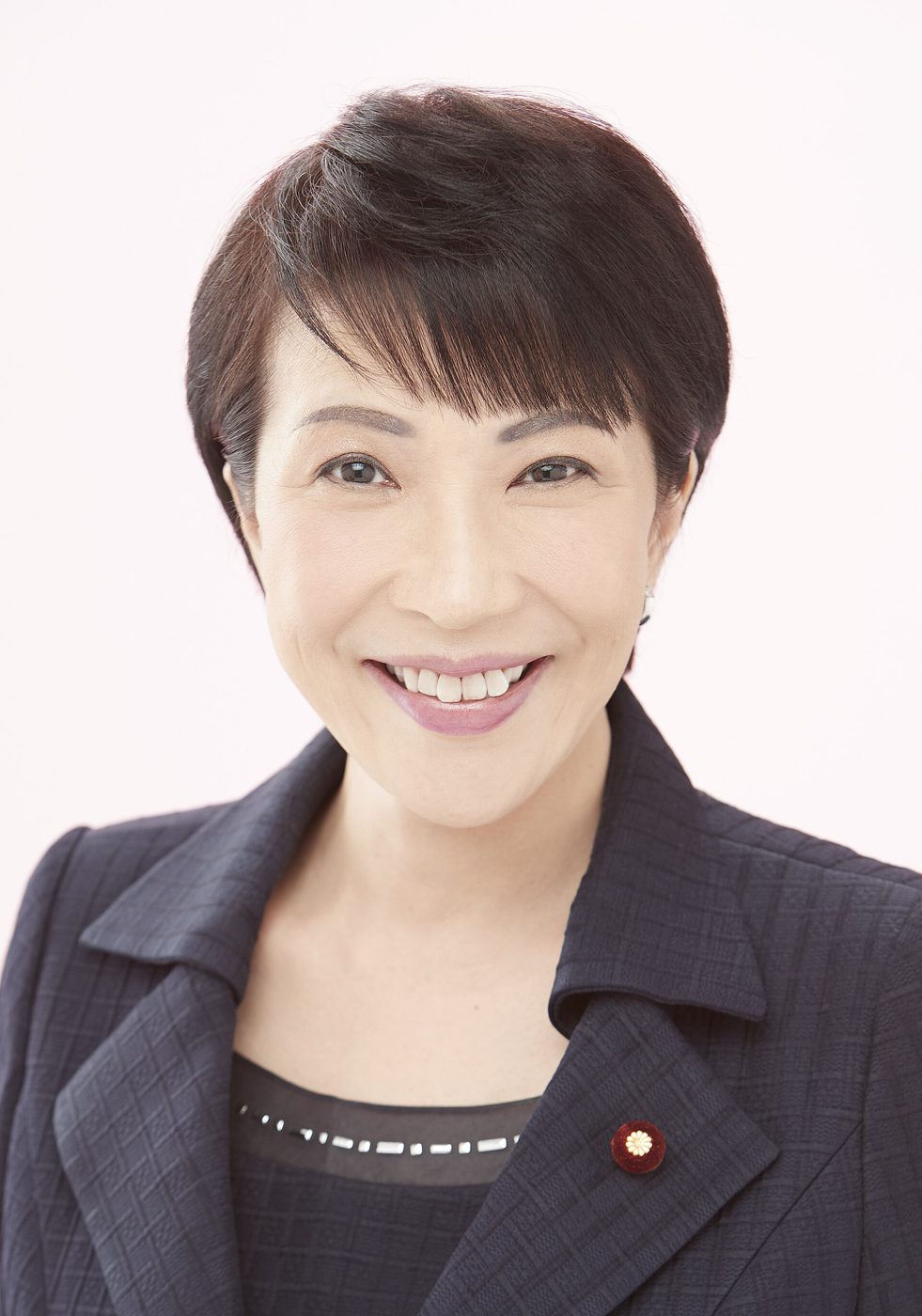 Sanae Takaichi in a formal portrait in front of a Japanese flag