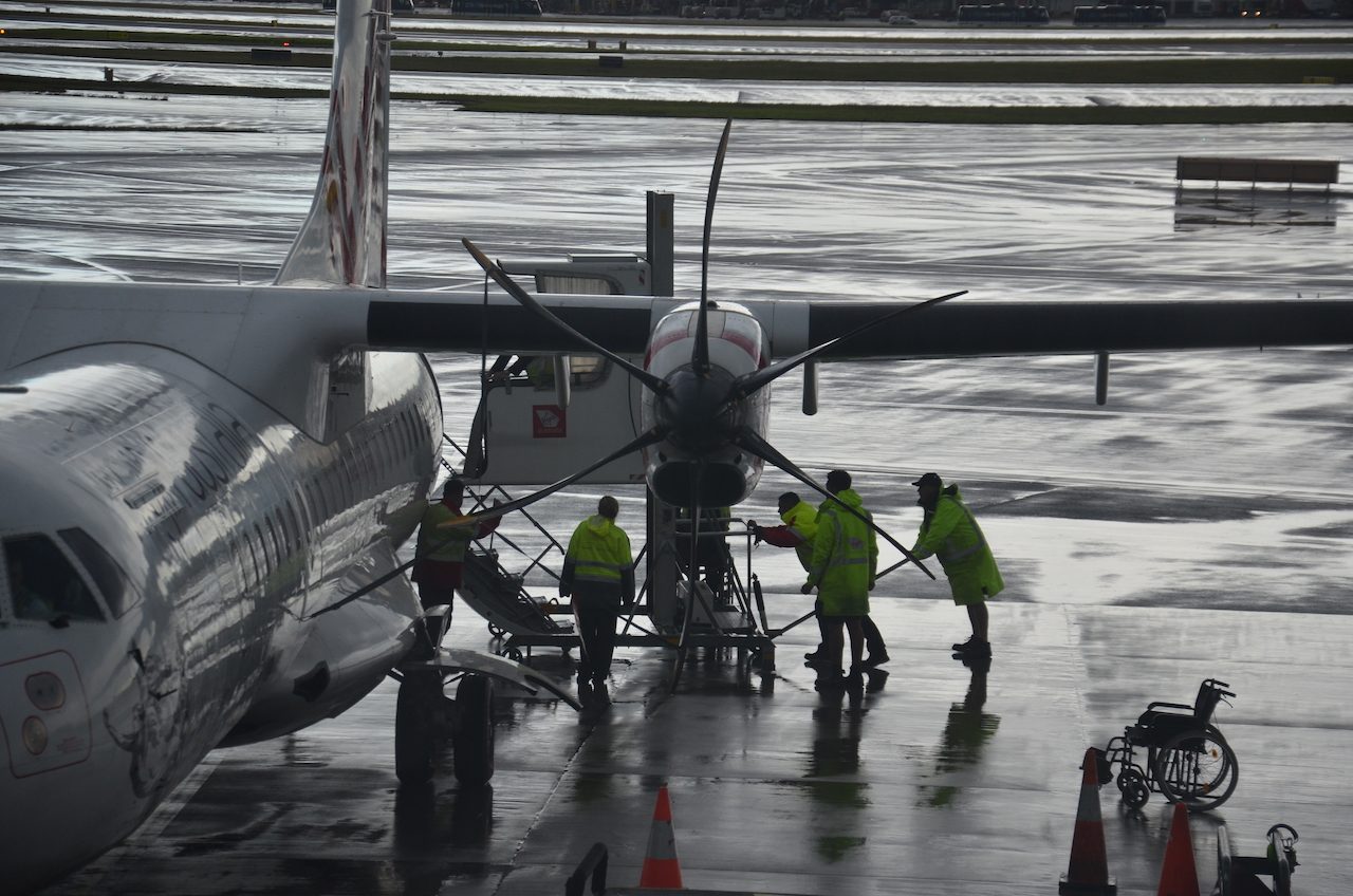 A ramp and lift equipment set up beside a small propeller plane for a wheelchair user