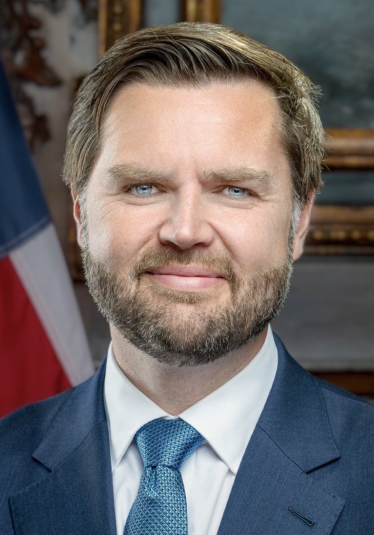 Official portrait of JD Vance in a dark suit in front of an American flag