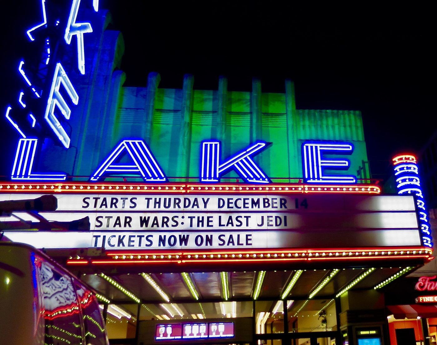 A brightly lit movie theater marquee at night