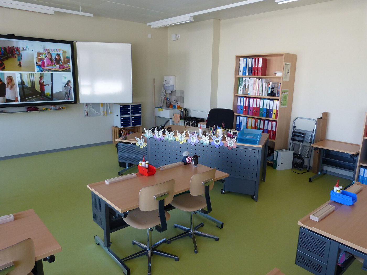 A school classroom with desks, chairs and a screen
