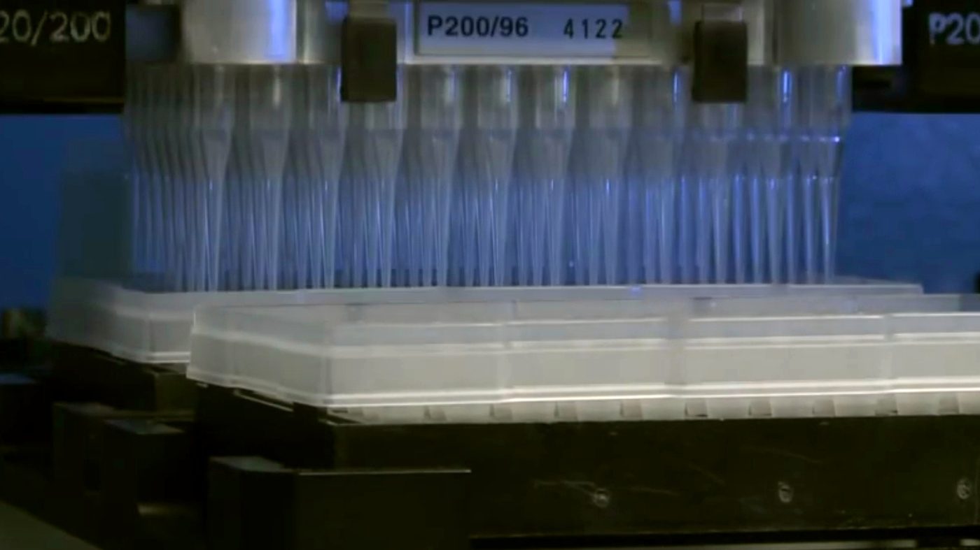 A robotic liquid-handling machine with rows of pipette tips in a lab