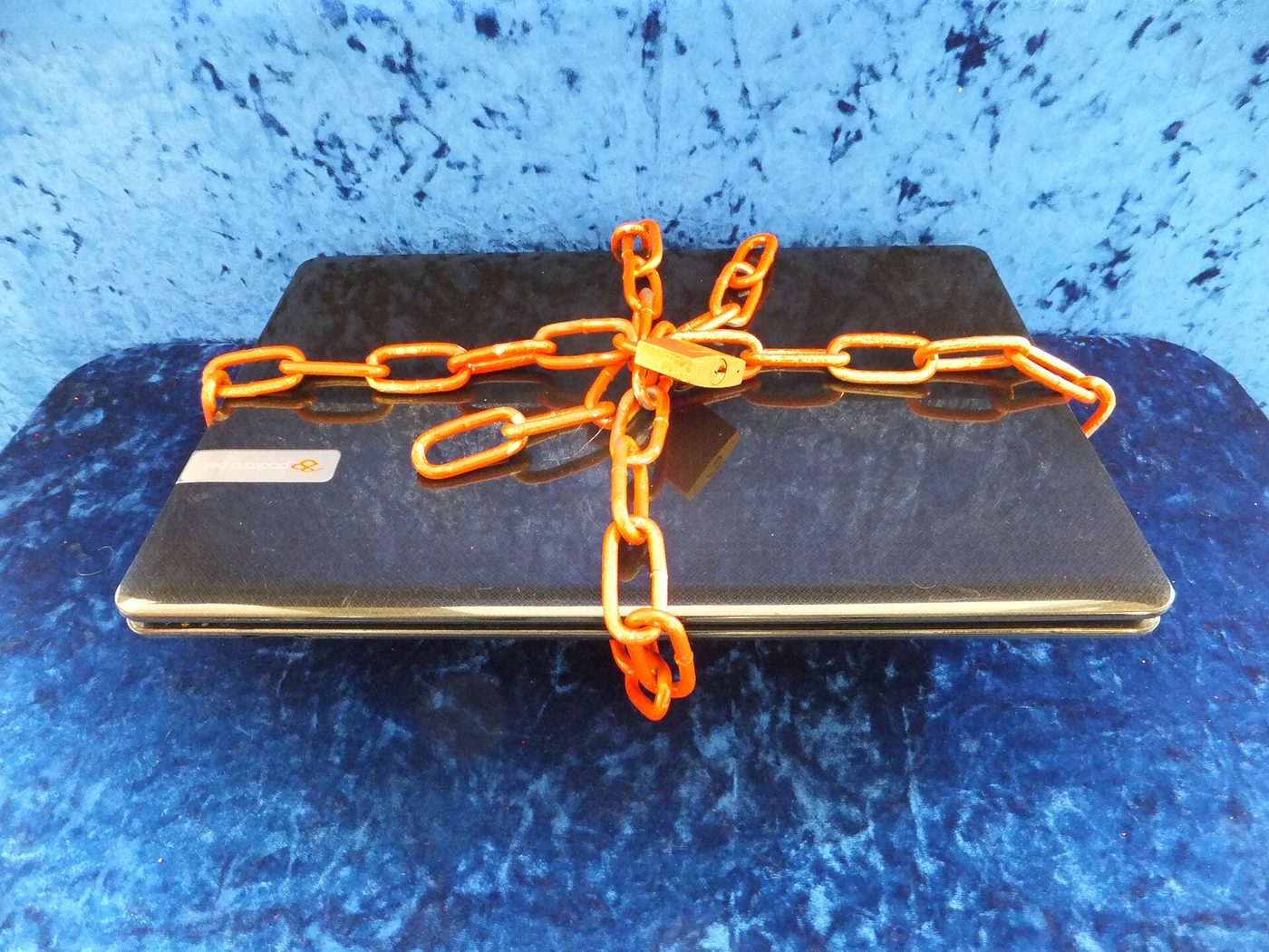 A laptop wrapped in an orange chain and padlock