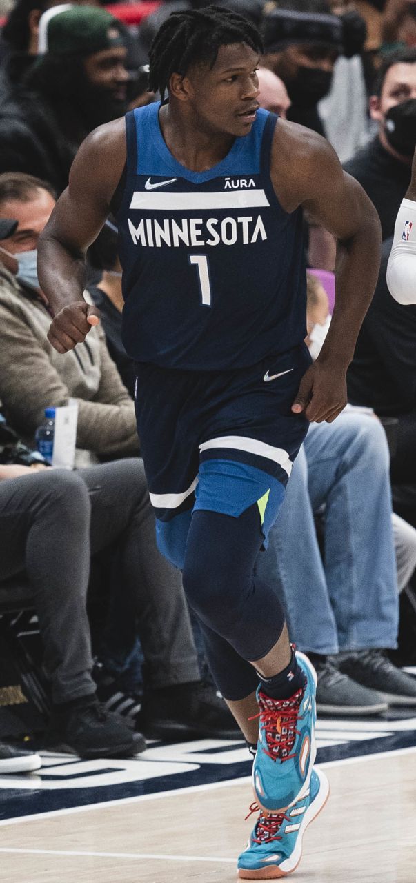 Anthony Edwards in a dark blue Minnesota jersey walks on the court during a game