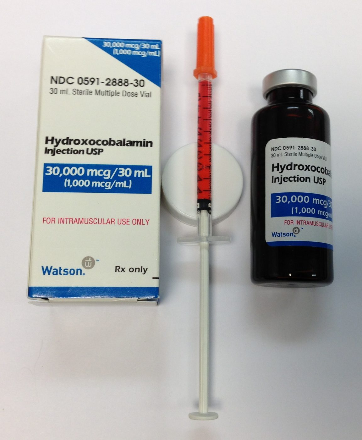 A syringe drawing liquid from a small injection vial