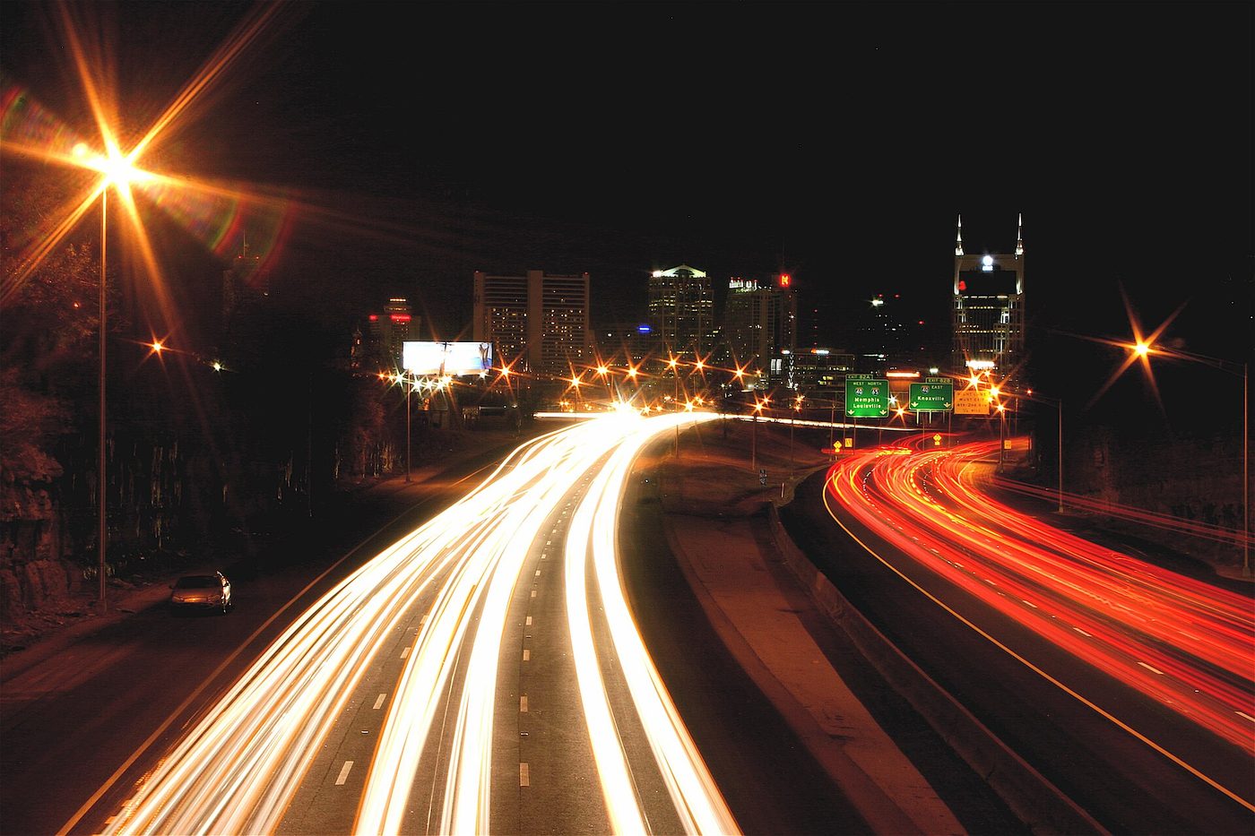 Nashville highway traffic streaks at night with the downtown skyline behind