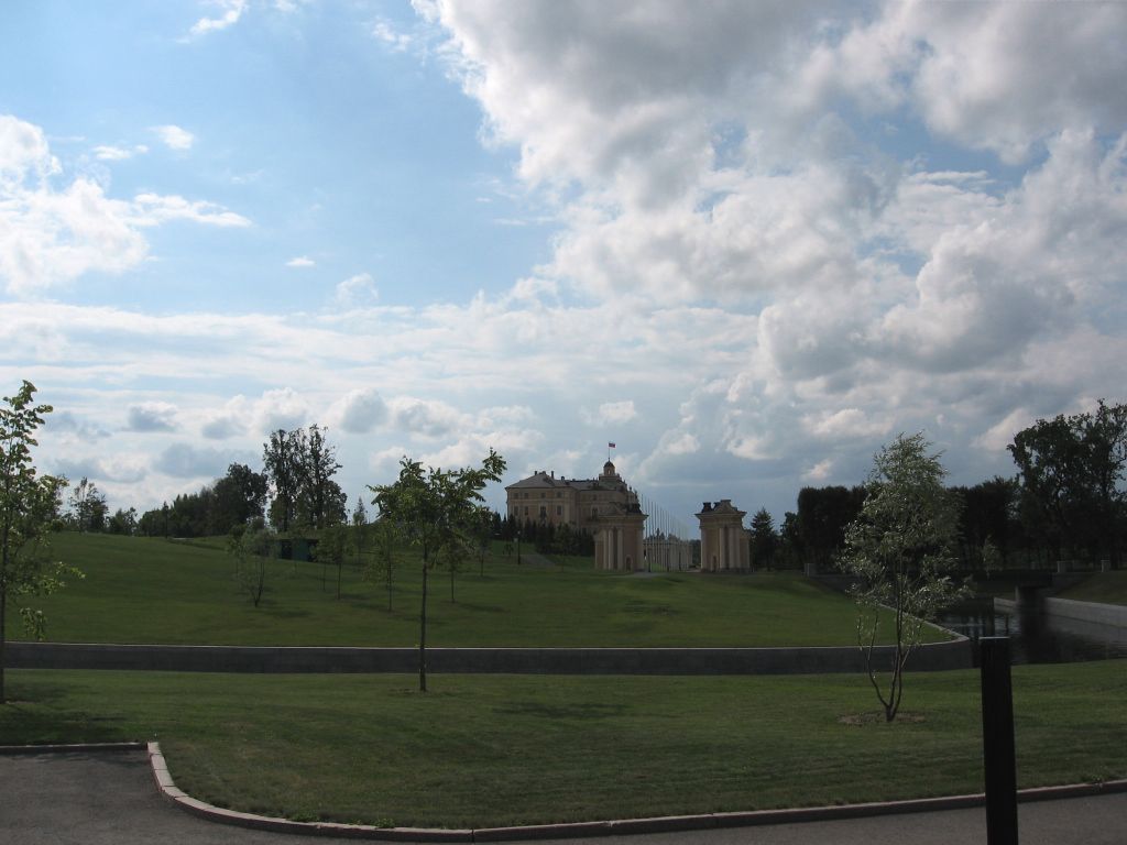 The Konstantinovsky Palace in the distance beyond a wide green lawn under a cloudy sky