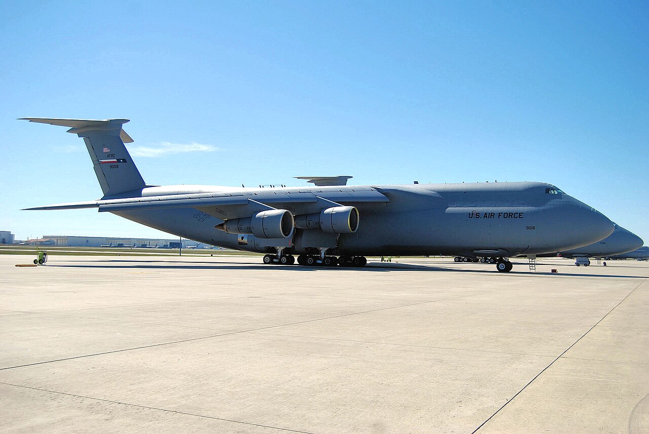A large gray Air Force C-5 cargo plane parked on a sunny airfield