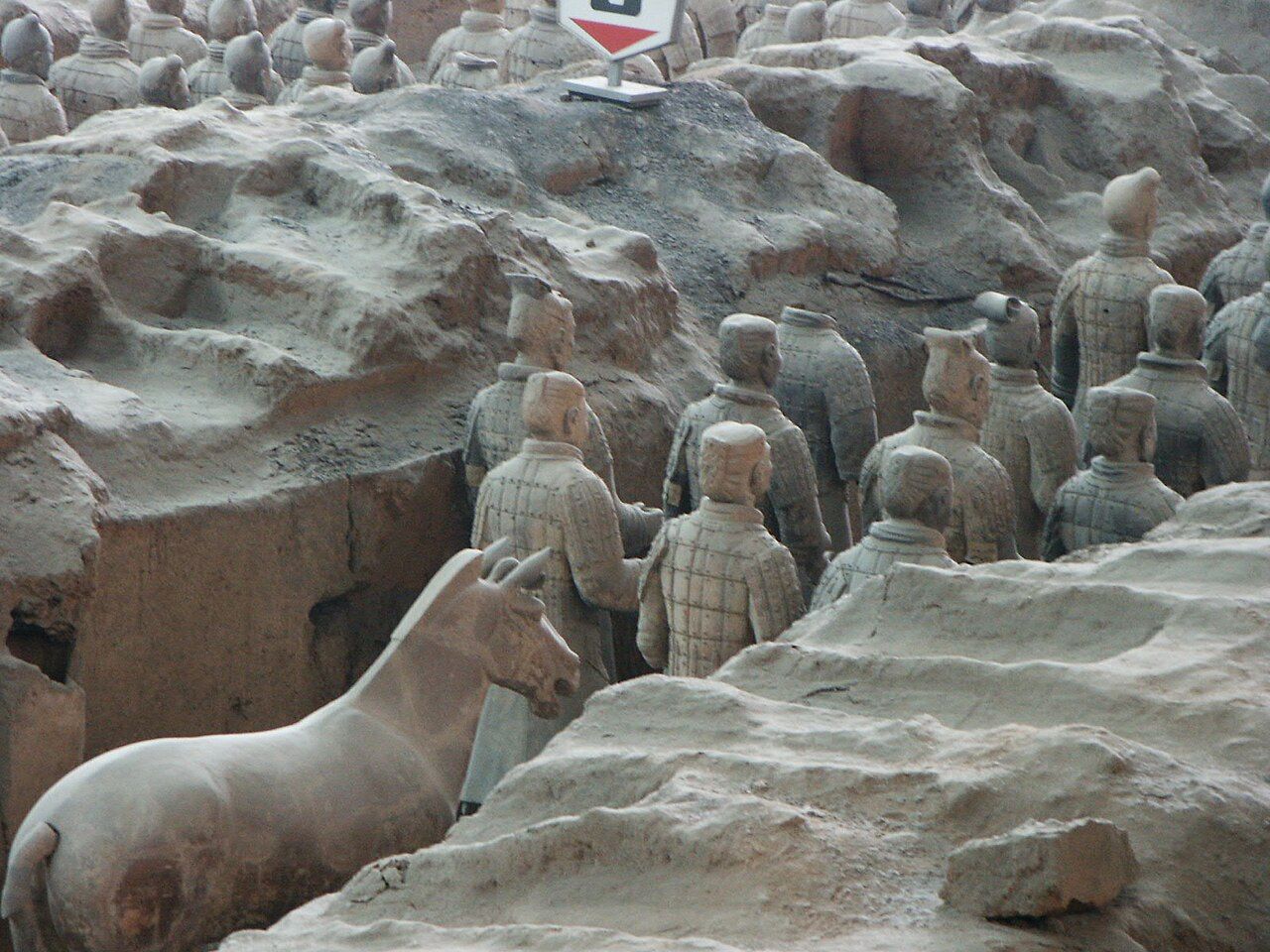 Rows of life-size clay soldiers and horses standing in an excavated trench