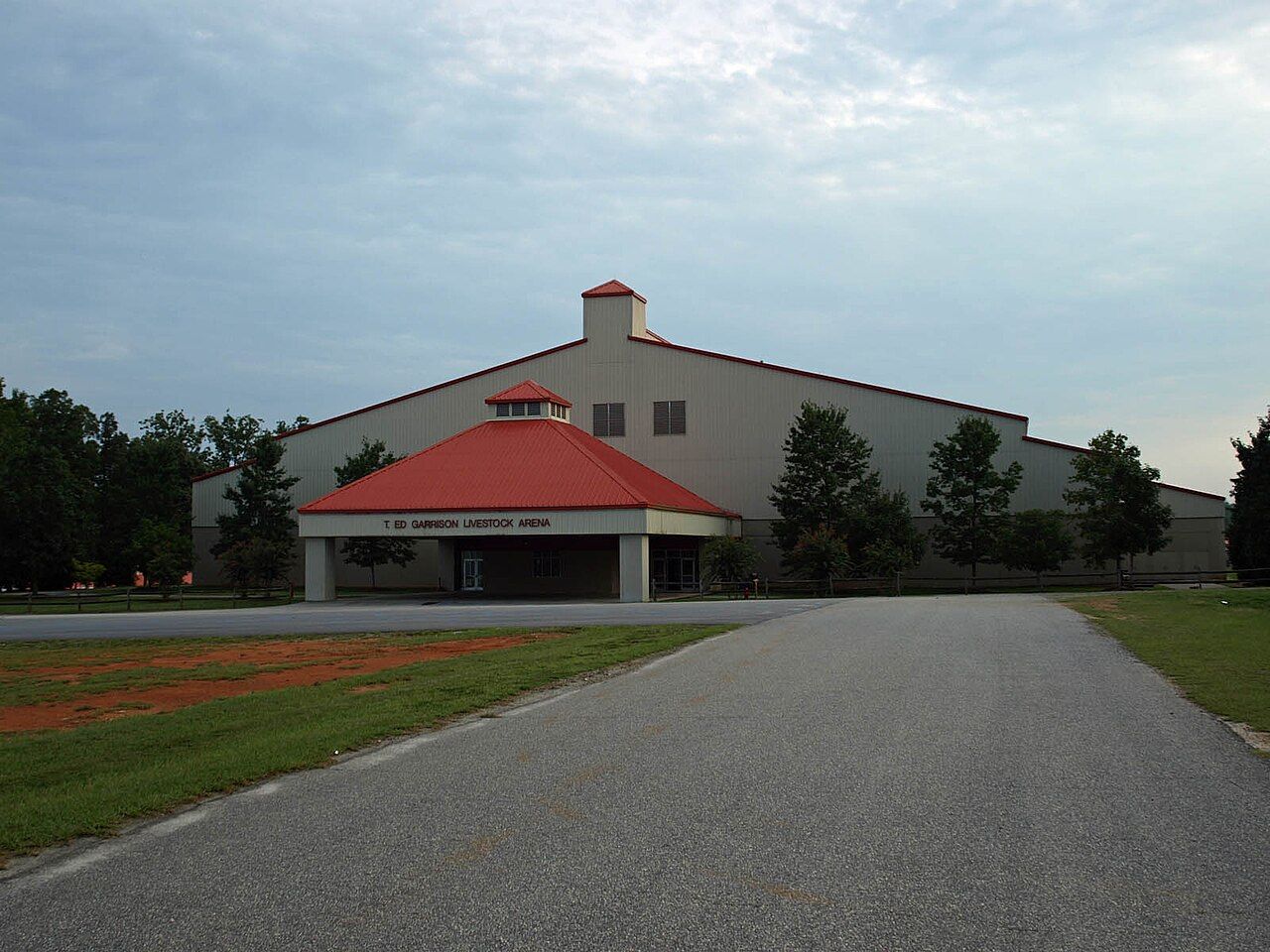 A large tan building with a red-roofed entrance marked T. Ed Garrison Livestock Arena