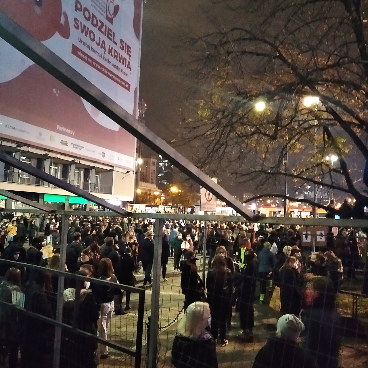 A crowd of protesters on a street in central Warsaw at night