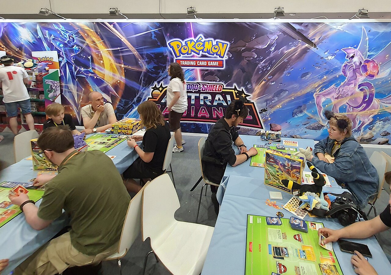 Players sit at tables playing the Pokémon Trading Card Game at a convention