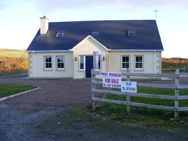 Several real estate signs stand in front of a house for sale