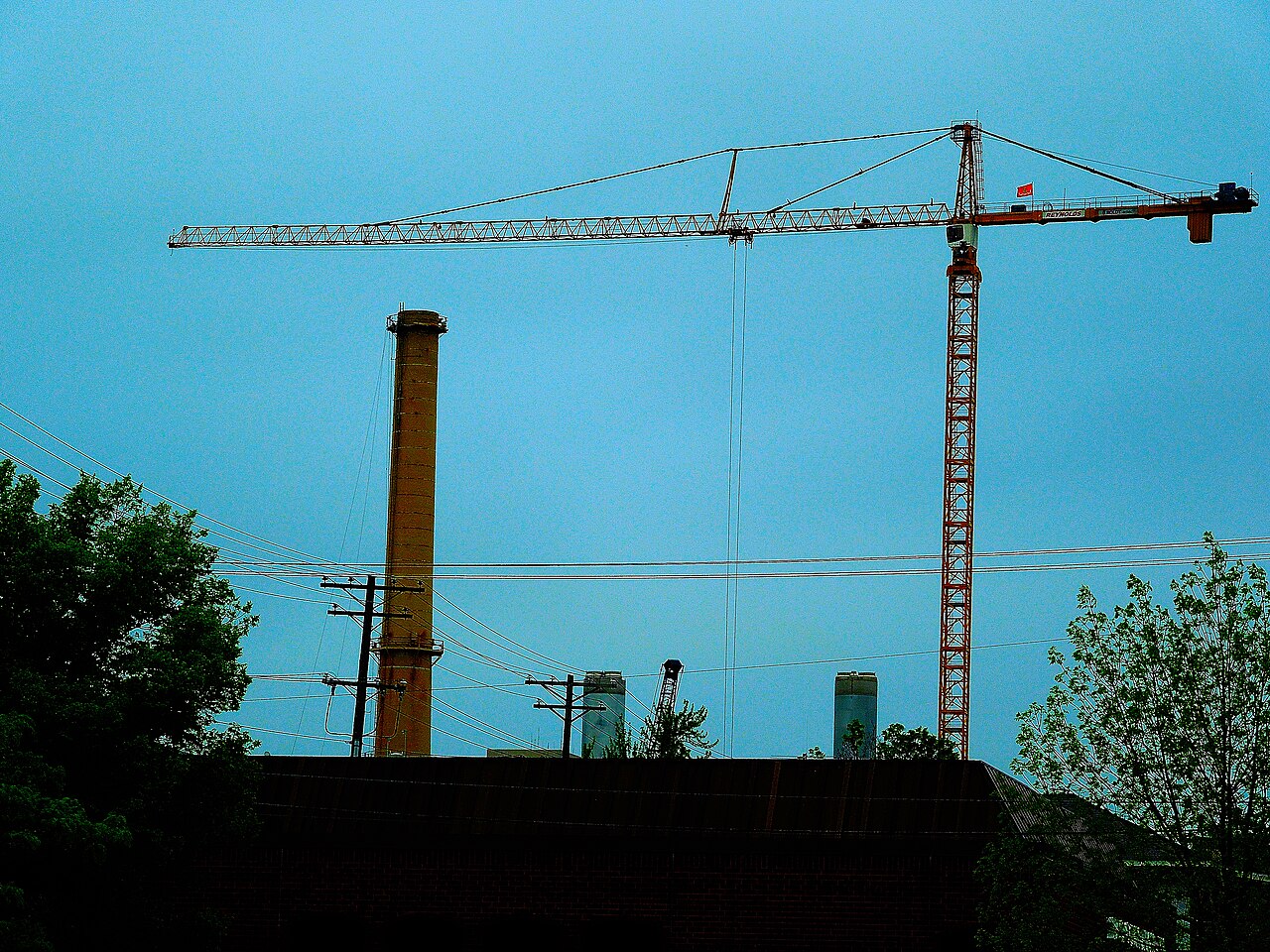 A tall industrial smokestack beside a large crane at a power plant