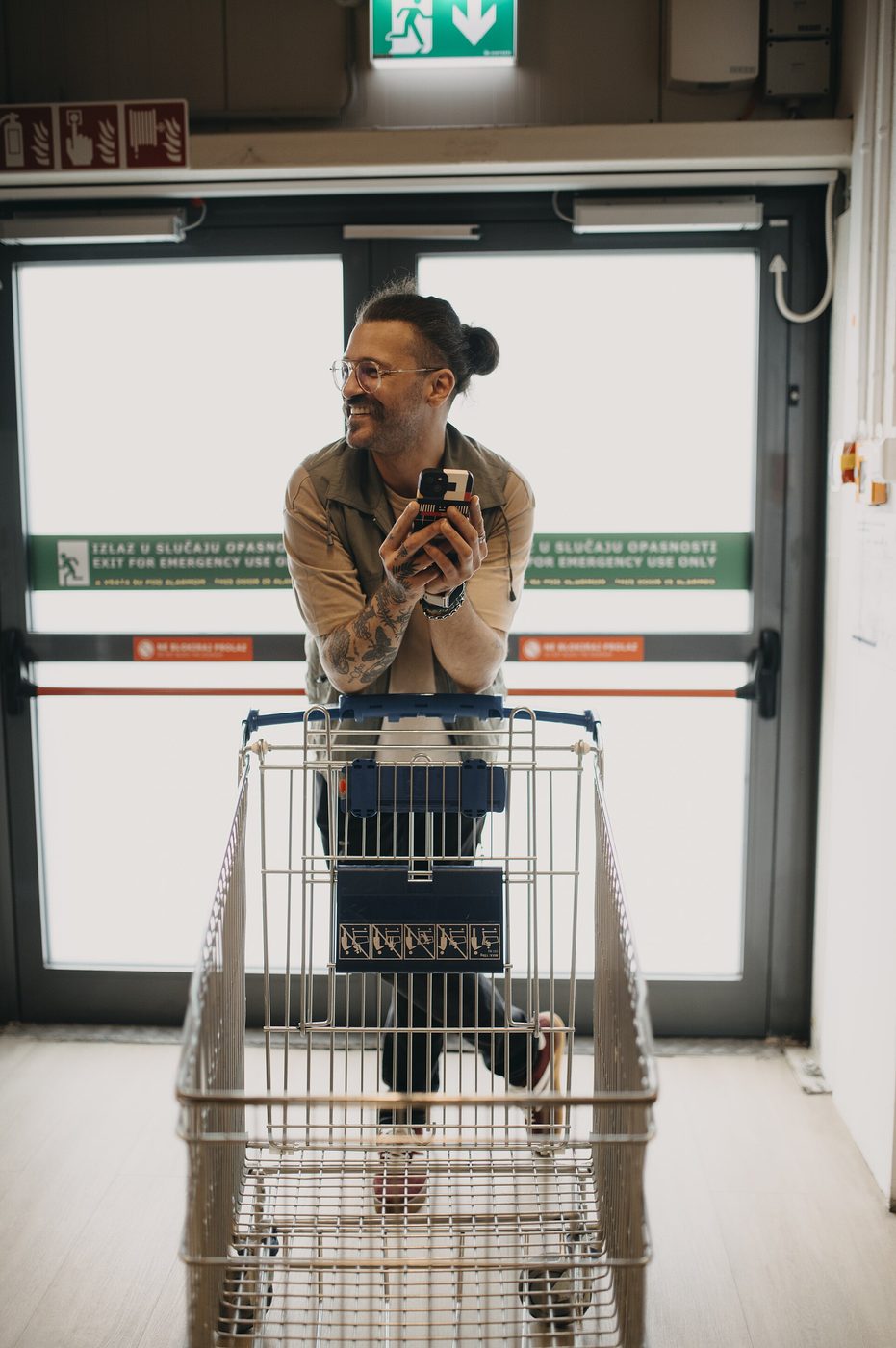 Shopper with smartphone and grocery cart in a store aisle