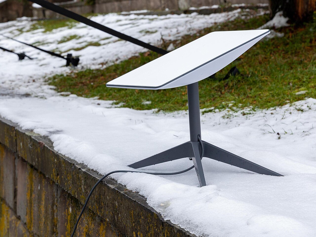 A Starlink satellite antenna resting on the ground outdoors