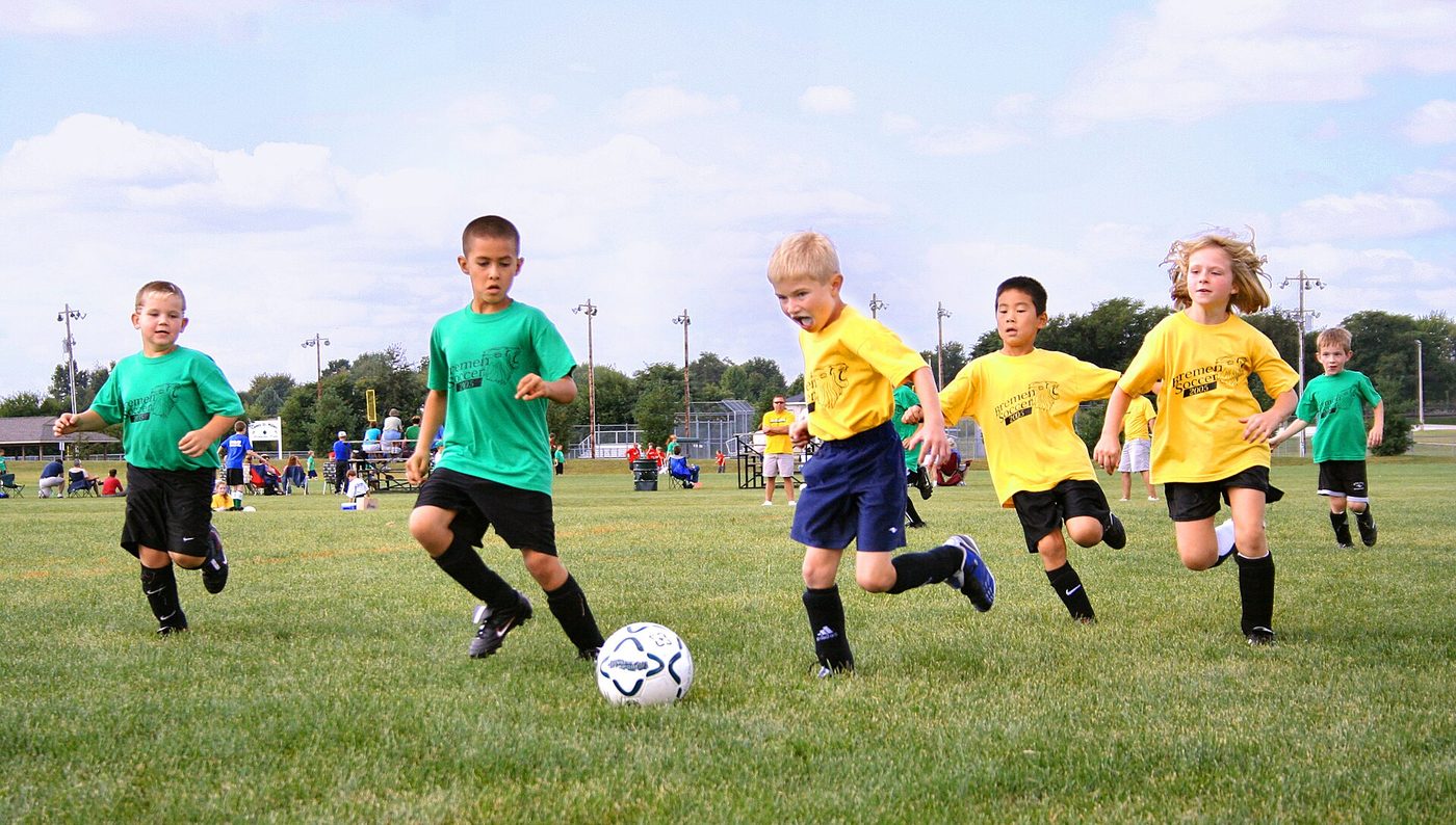Children playing youth soccer on a grass field