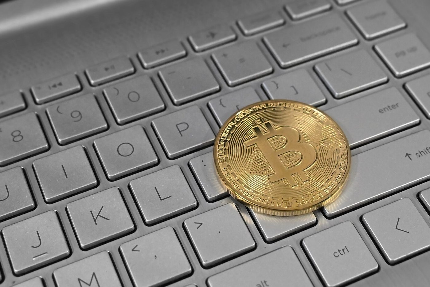 Bitcoin coin resting on a laptop keyboard