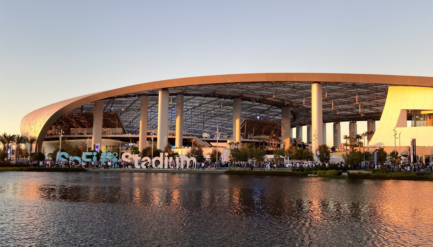 SoFi Stadium in Inglewood, California, seen across a lake at dusk