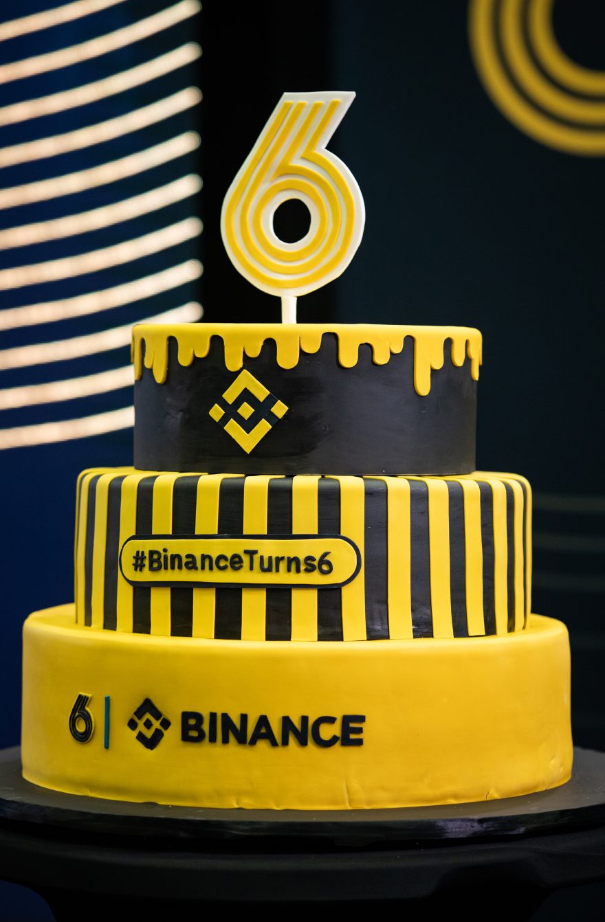 A cake decorated with a gold number 6 and the Binance logo