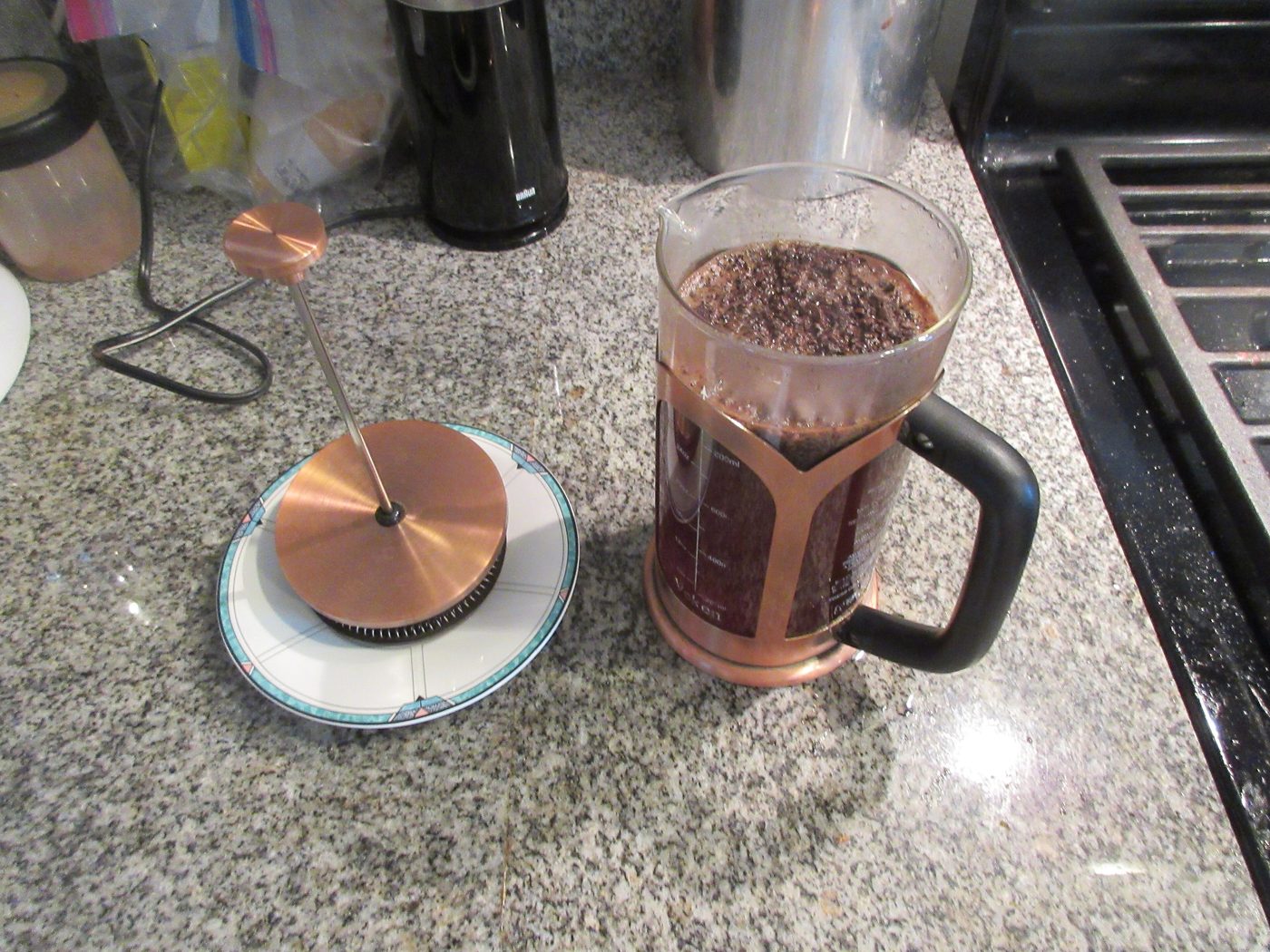 A glass French press coffee maker on a kitchen counter