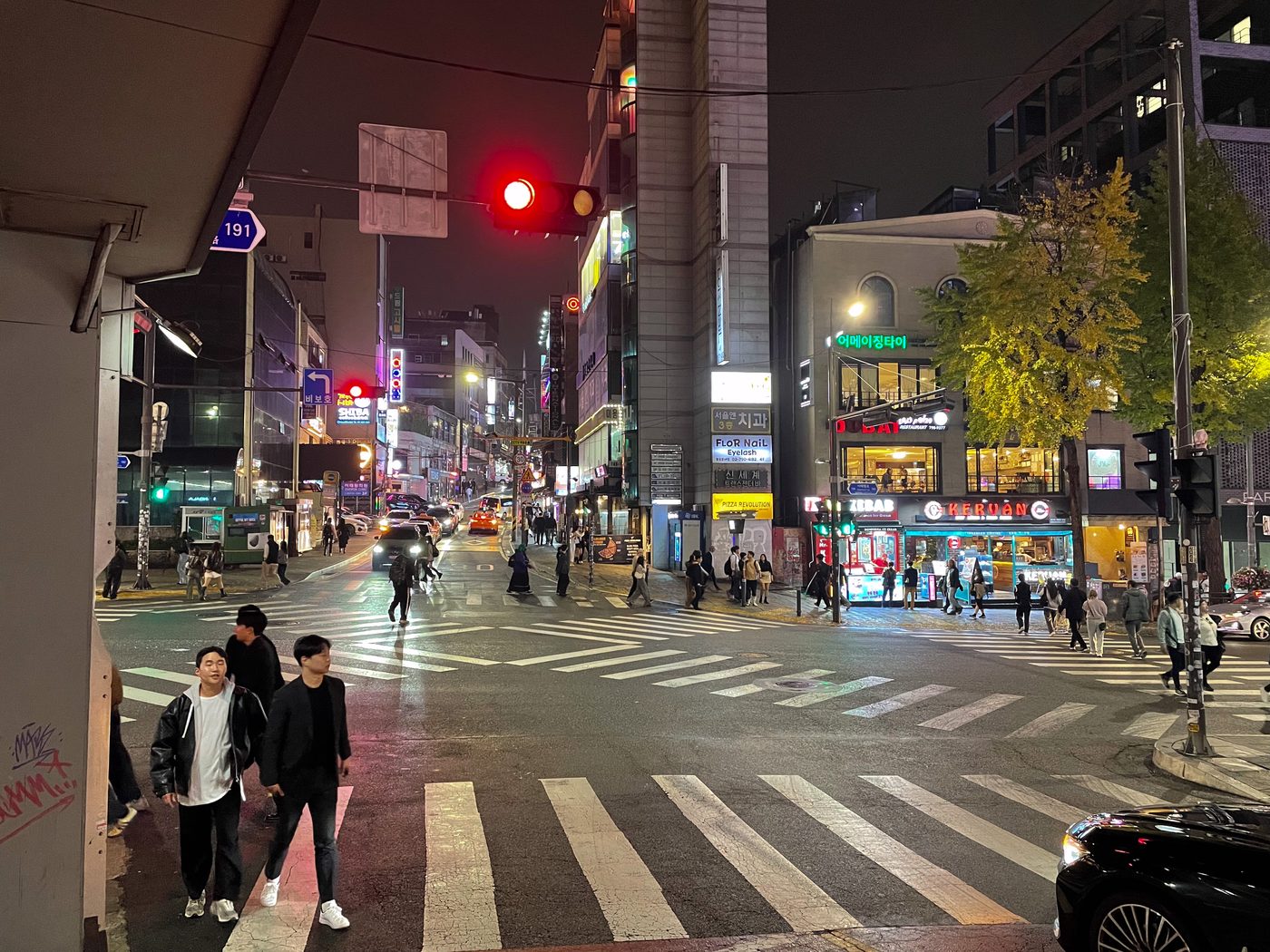 A street in Itaewon, Seoul, at night with neon signs and people walking