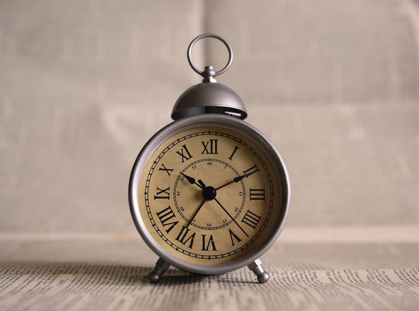 A brass alarm clock with Roman numerals on a table