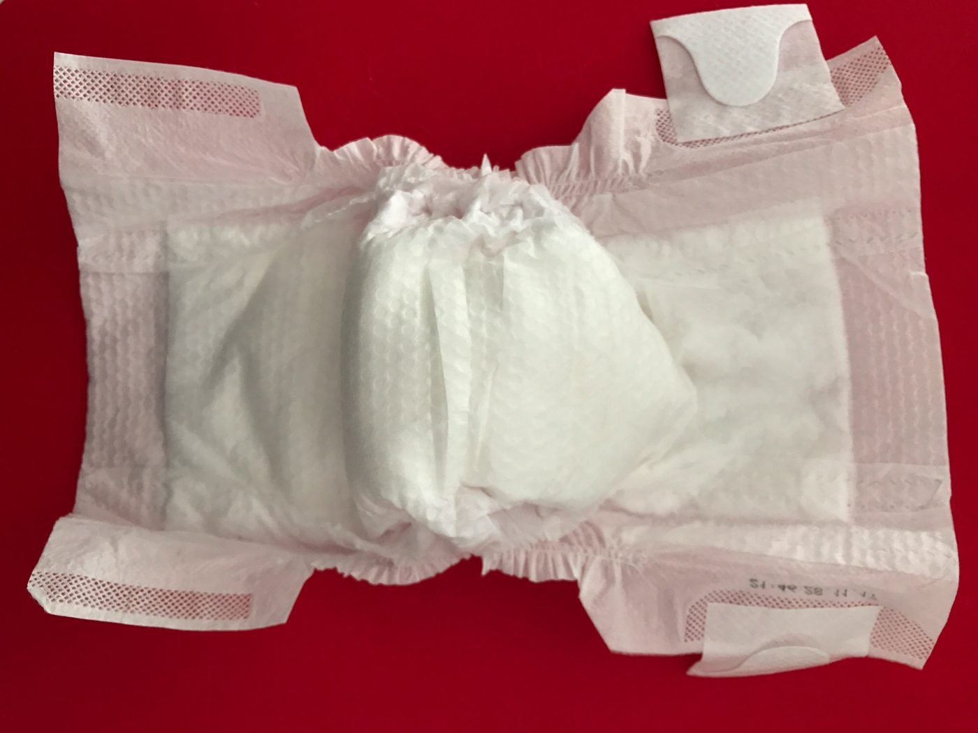 A white disposable baby diaper on a red background