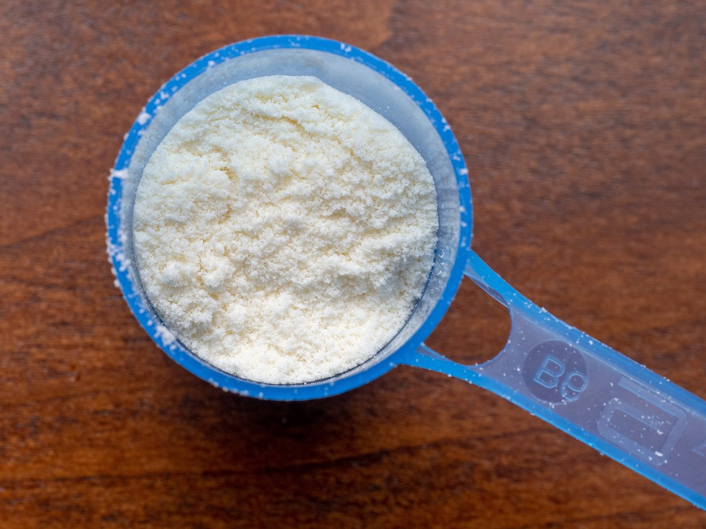 A blue scoop full of white baby formula powder