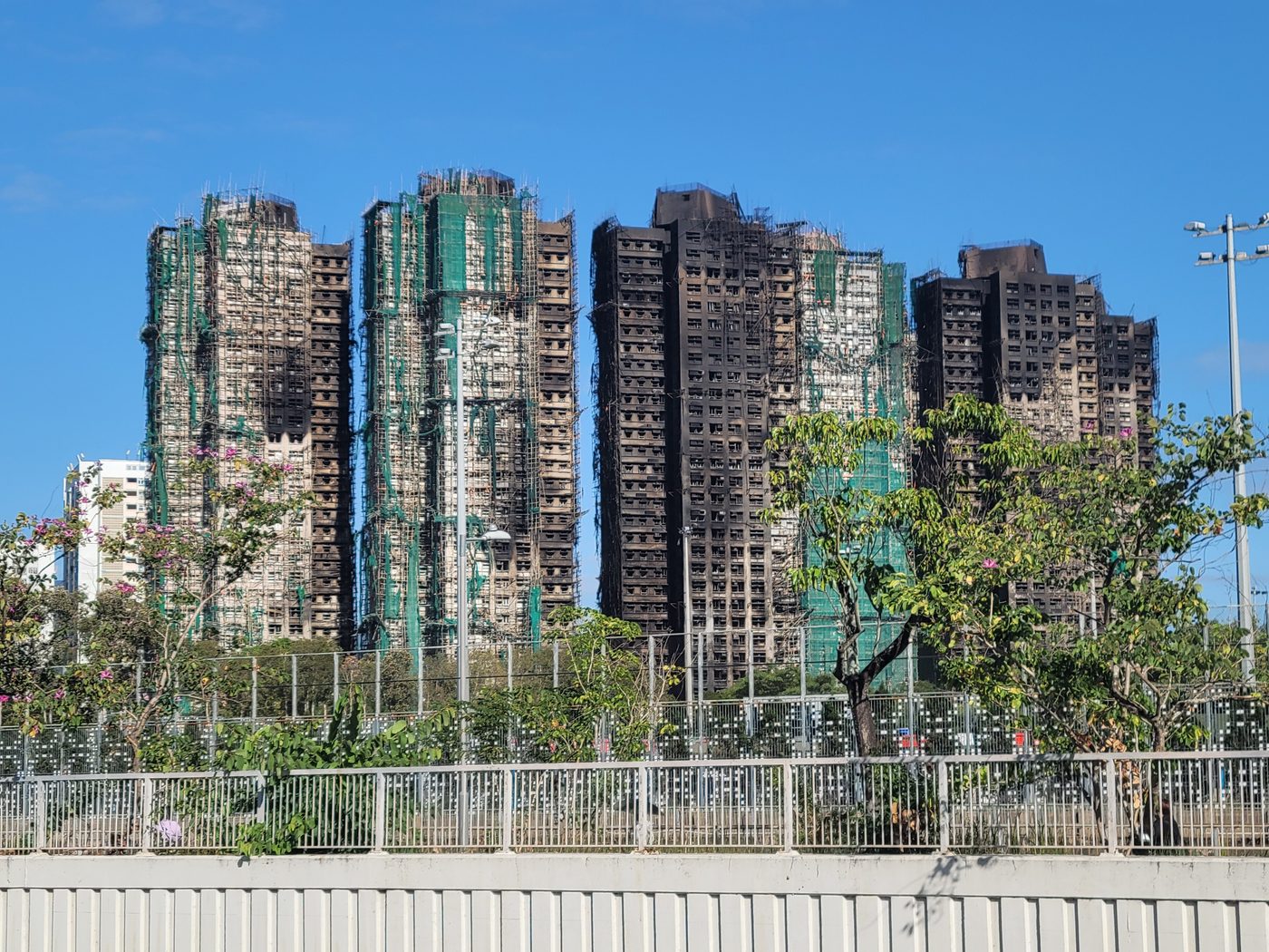 Burned tower blocks wrapped in scaffolding and green netting
