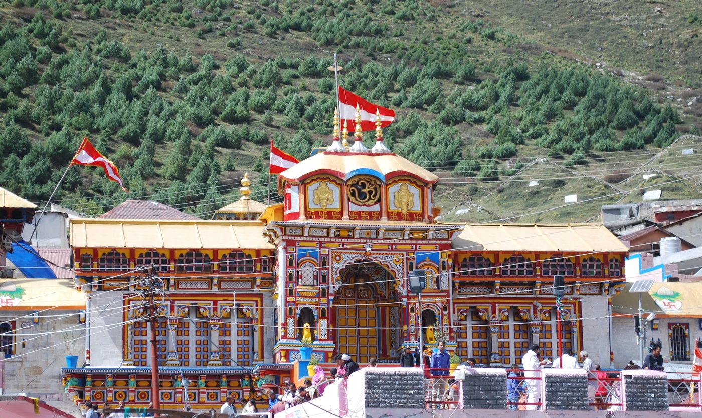 The brightly painted Badrinath temple with mountains behind it