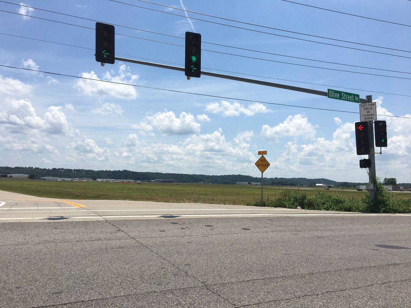 A road sign and lights near the Spirit of St. Louis Airport under a blue sky