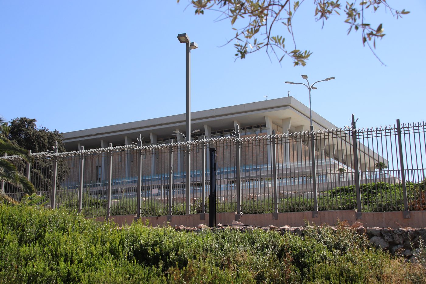 The Knesset building in Jerusalem behind a fence and trees