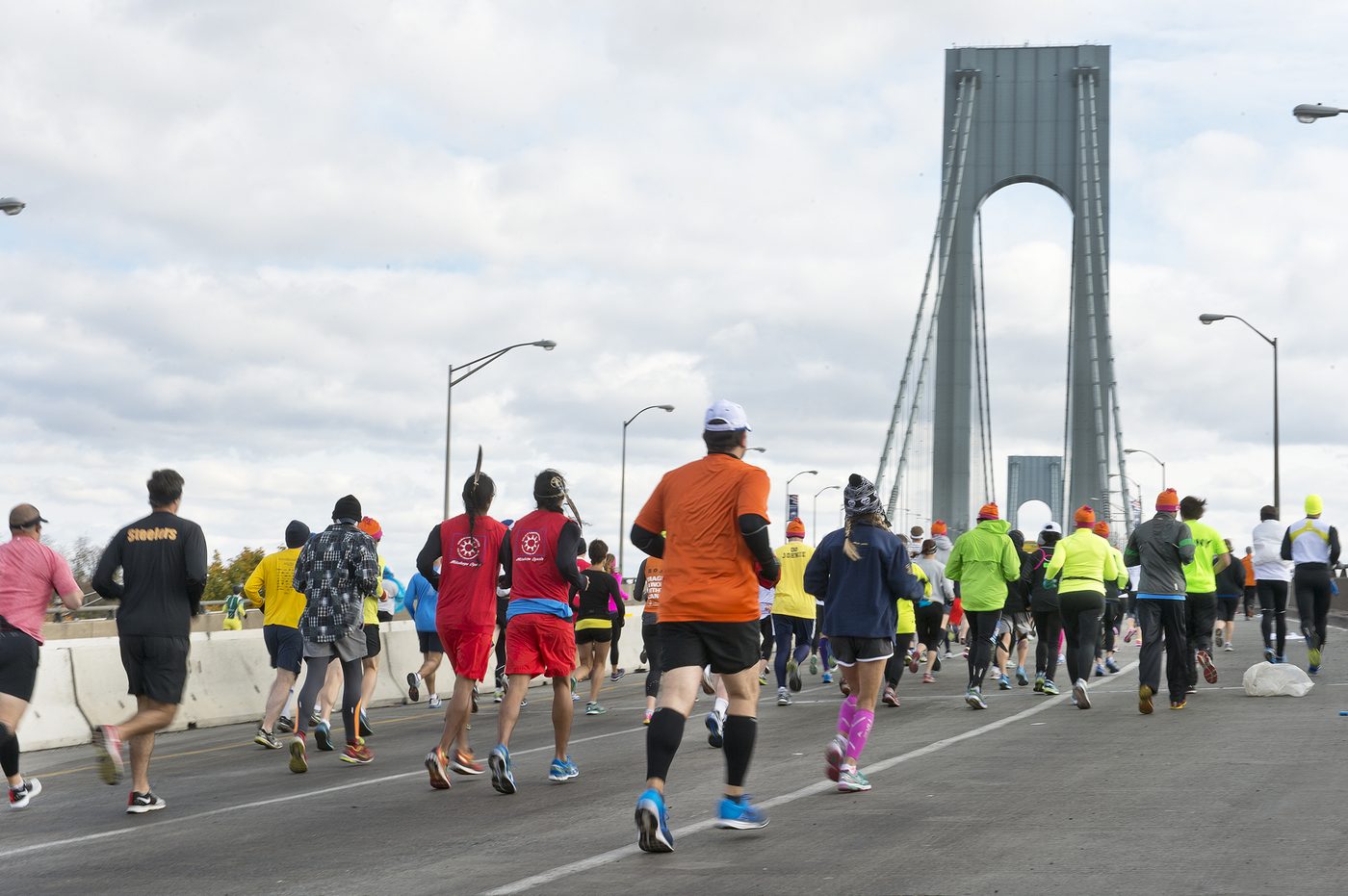Runners on a road with the Verrazzano bridge towers behind them