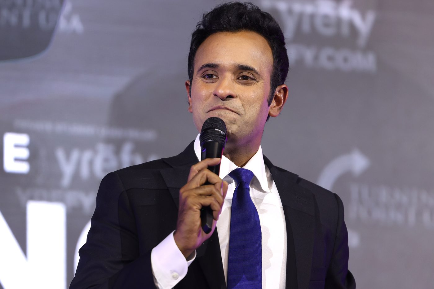 Vivek Ramaswamy in a dark suit speaking into a microphone