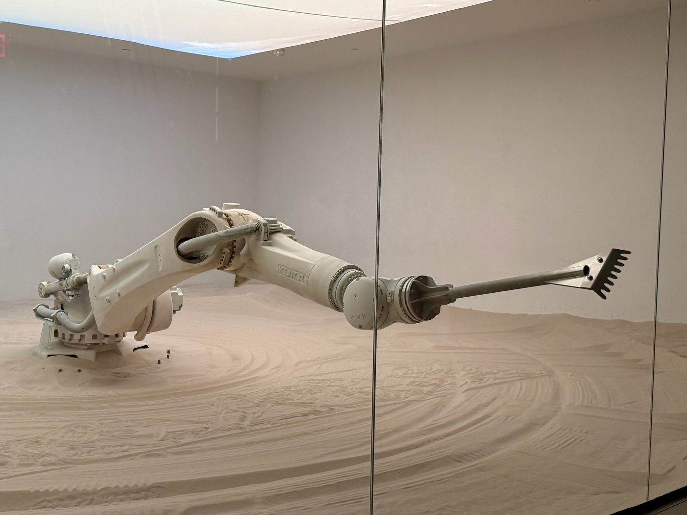 An orange industrial robot arm moving inside a gallery space
