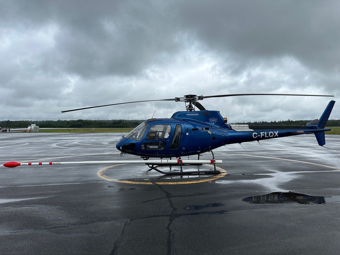A blue Airbus H125 helicopter parked on a landing pad