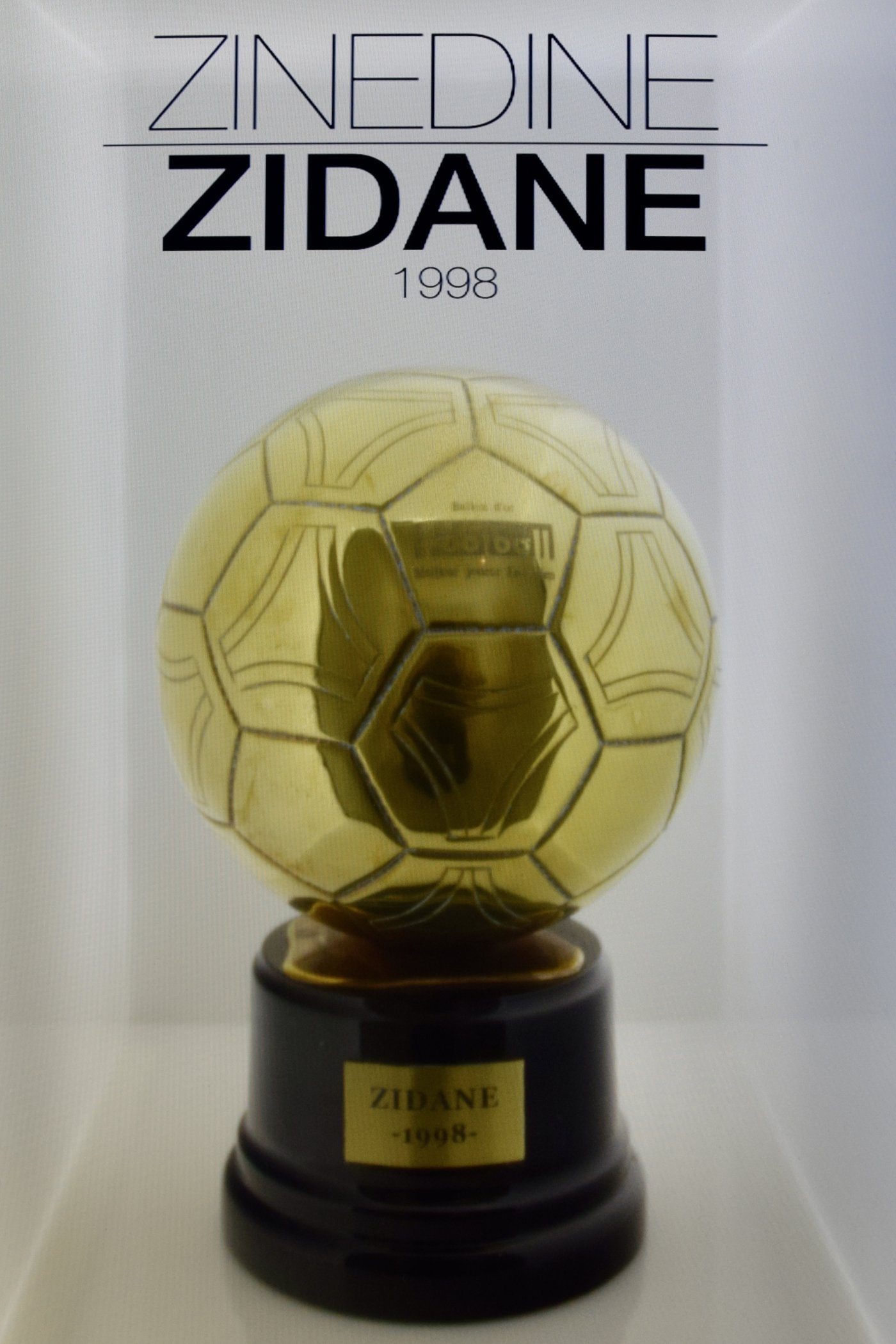 A golden Ballon d'Or trophy in a museum display case
