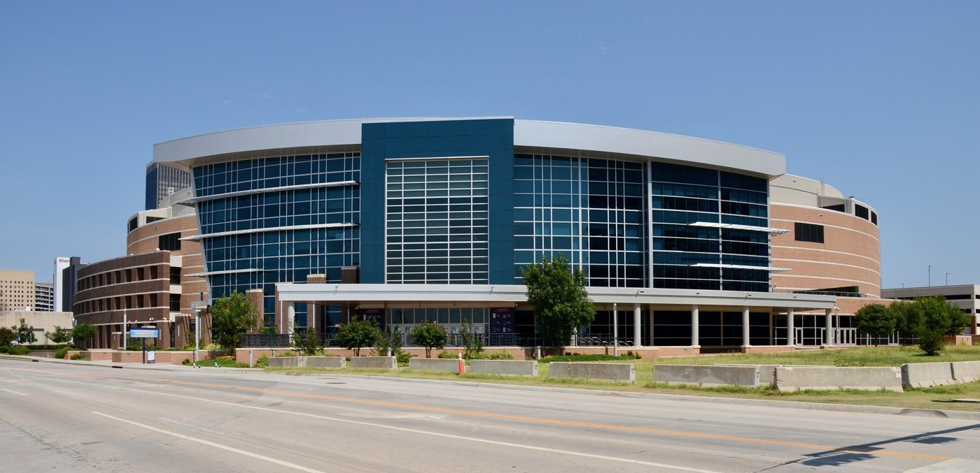 The glass and blue Paycom Center arena in Oklahoma City under a clear sky