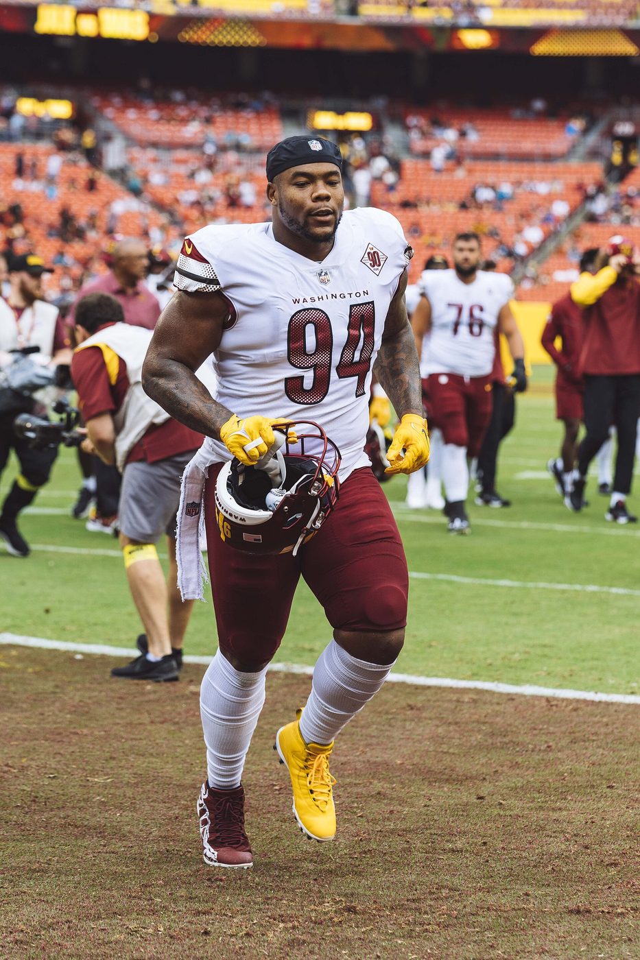 Daron Payne, number 94, runs onto the field in a white Washington uniform