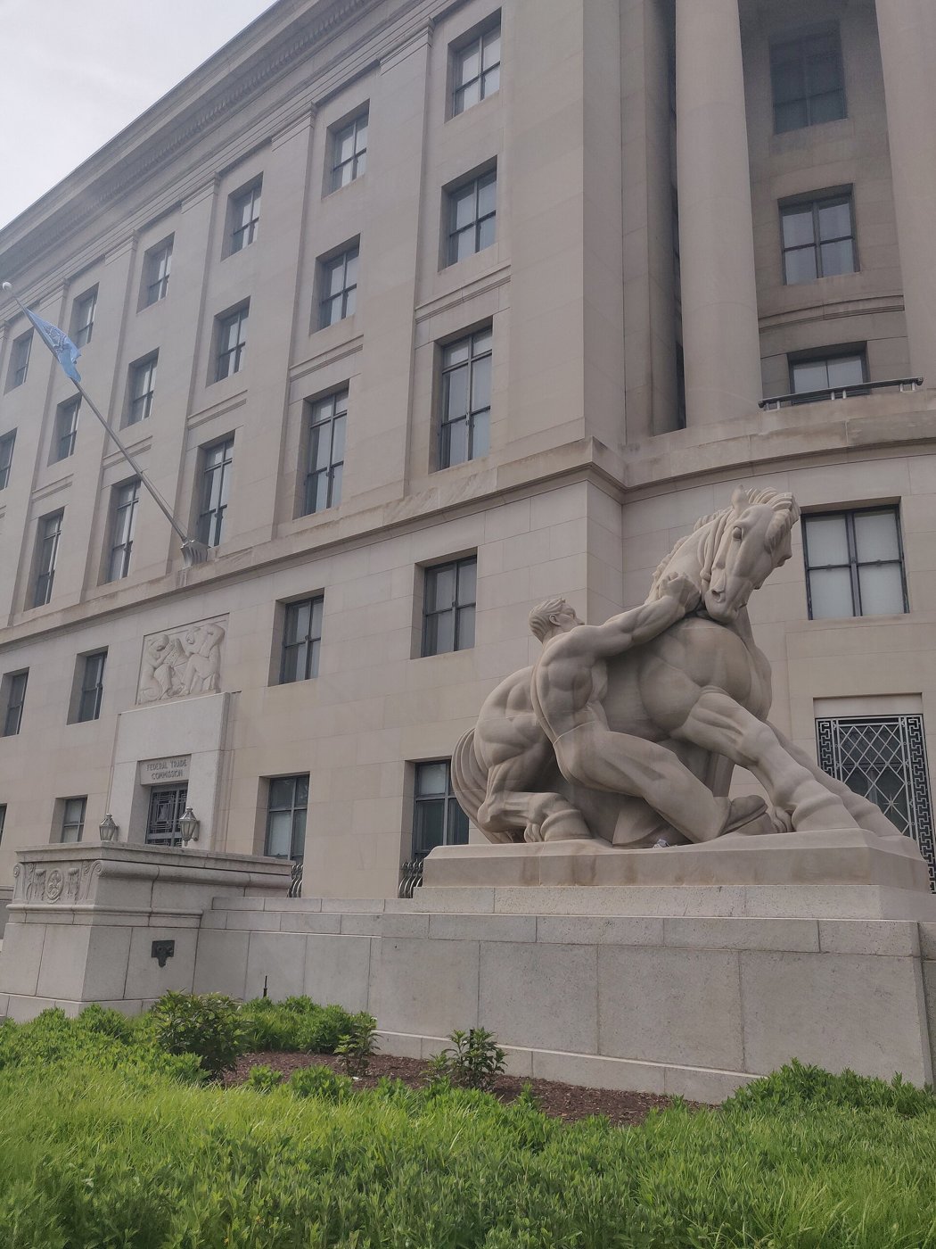 The stone Federal Trade Commission building in Washington, with a statue of a man holding back a horse in front