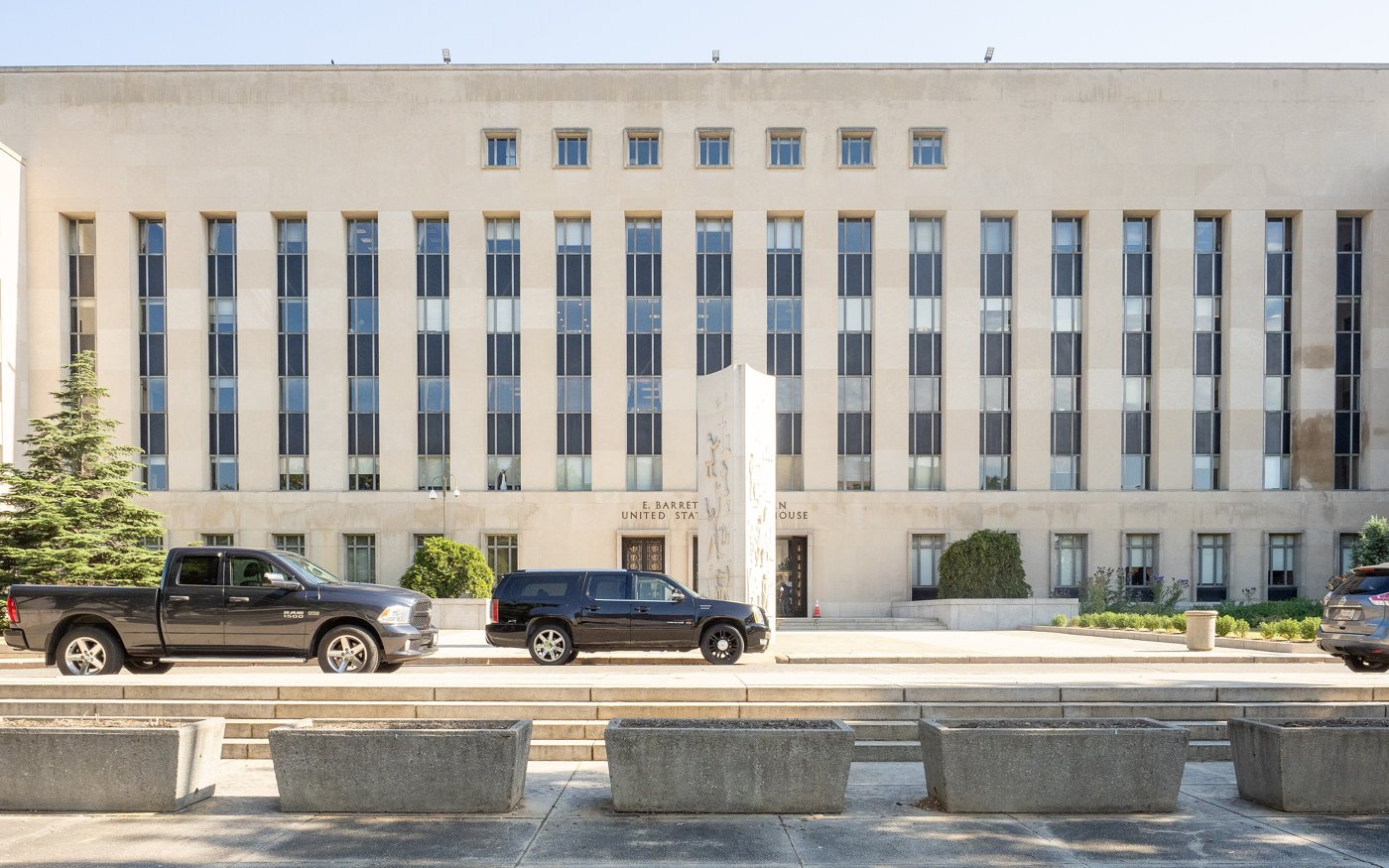 The pale stone E. Barrett Prettyman federal courthouse in Washington with cars parked in front