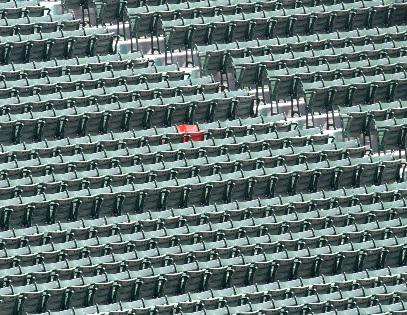 Rows of empty green stadium seats with a single red seat at Fenway Park