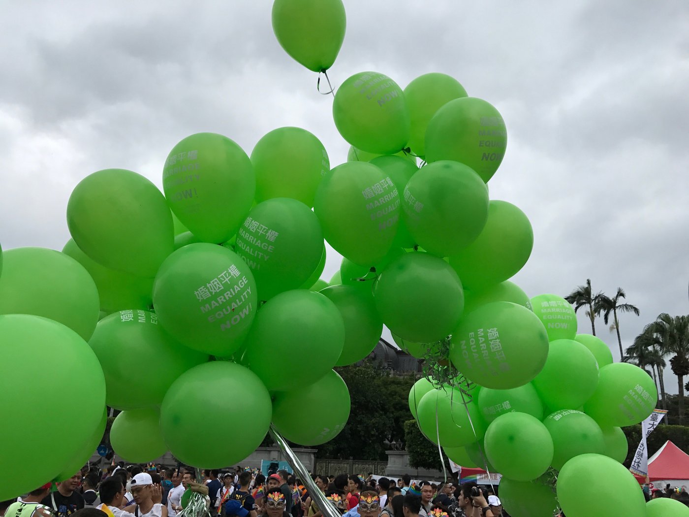 Green balloons rise above a crowd at the Taiwan Pride parade