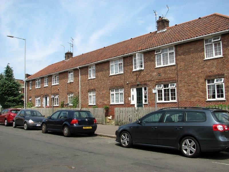 A row of brick terraced houses along a quiet English street